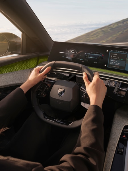 Mann beim Fahren eines PEUGEOT E-5008, Detailansicht des i-Cockpit.